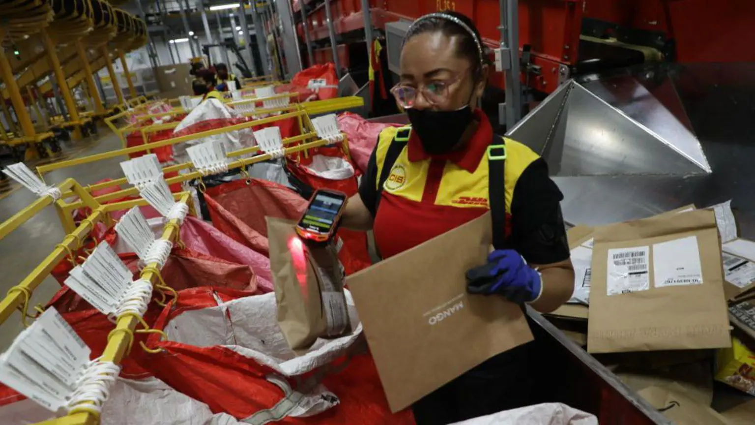Жінка обробляє пакунки на жвавому складі доставки DHL