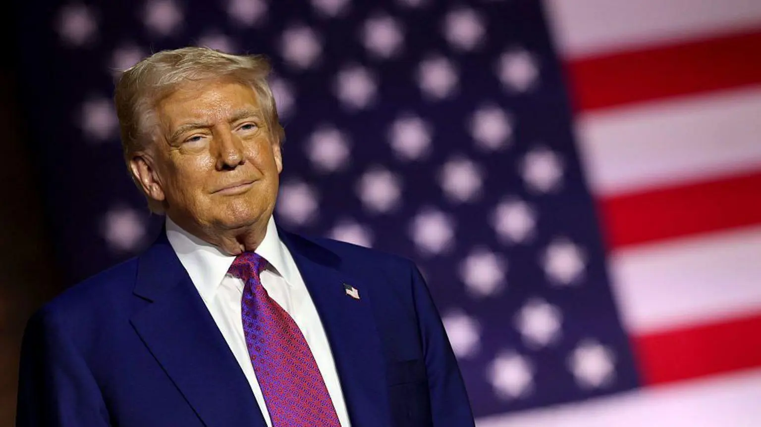 Дональд Трамп стоїть перед прапором США