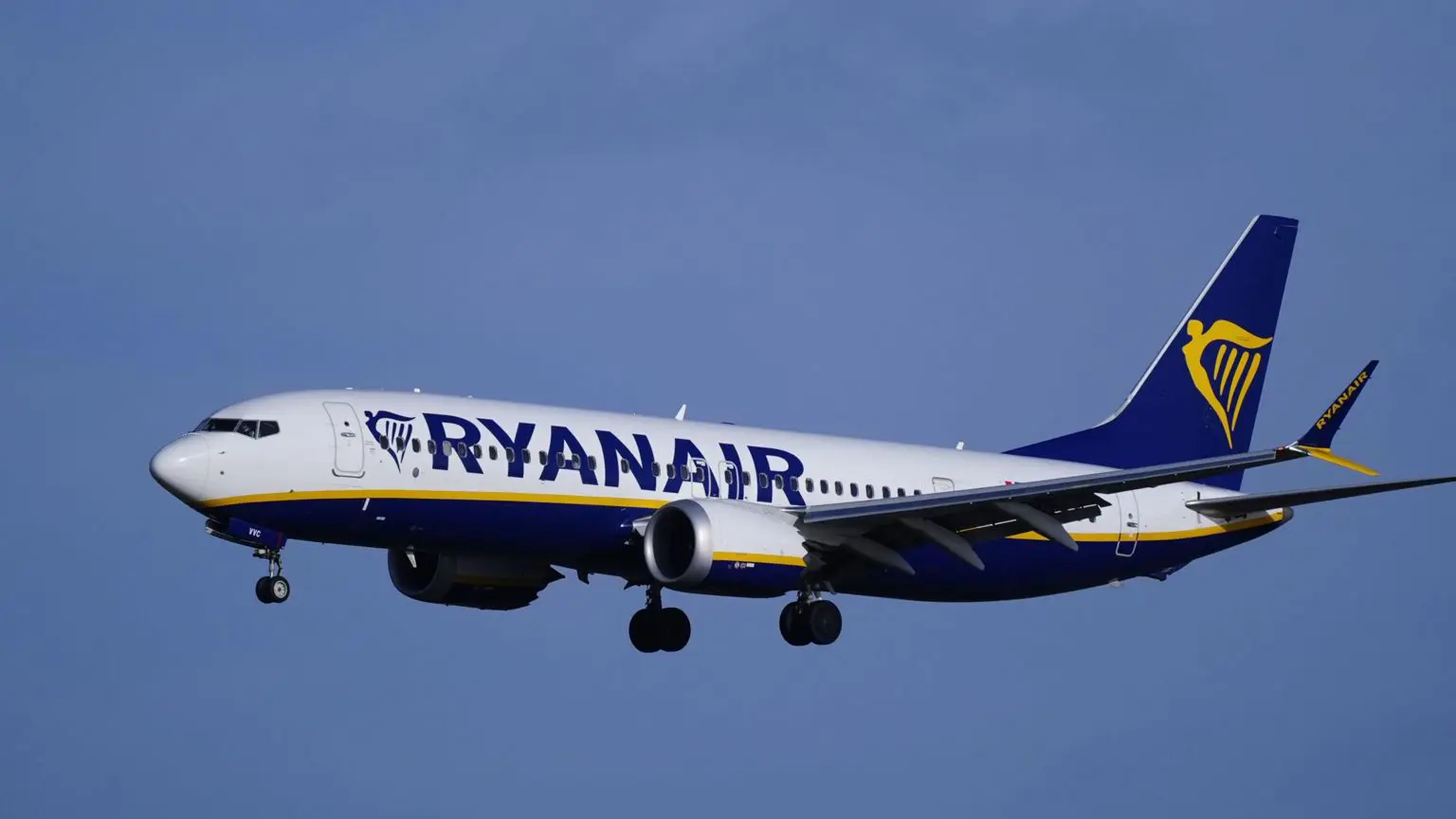 Рейс Ryanair, що летить на тлі блакитного неба, із золотим брендингом у формі арфи на задній частині літака та написом Ryanair на боці