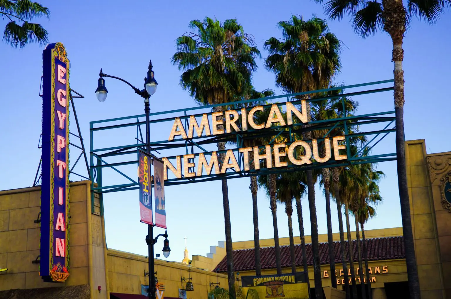 Вид на зовнішній вигляд Єгипетського театру в Лос-Анджелесі. Його назва освітлена вогнями на шатрі, а на іншому неоновому знаку написано «Американська сінематека».
