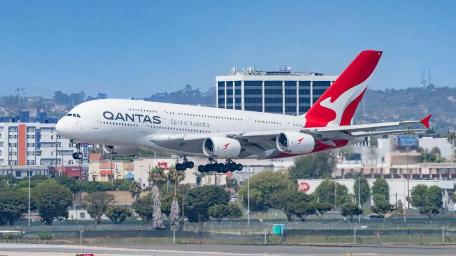 Airbus A380 Qantas Airways заходить на посадку в міжнародному аеропорту Лос-Анджелеса на тлі міста