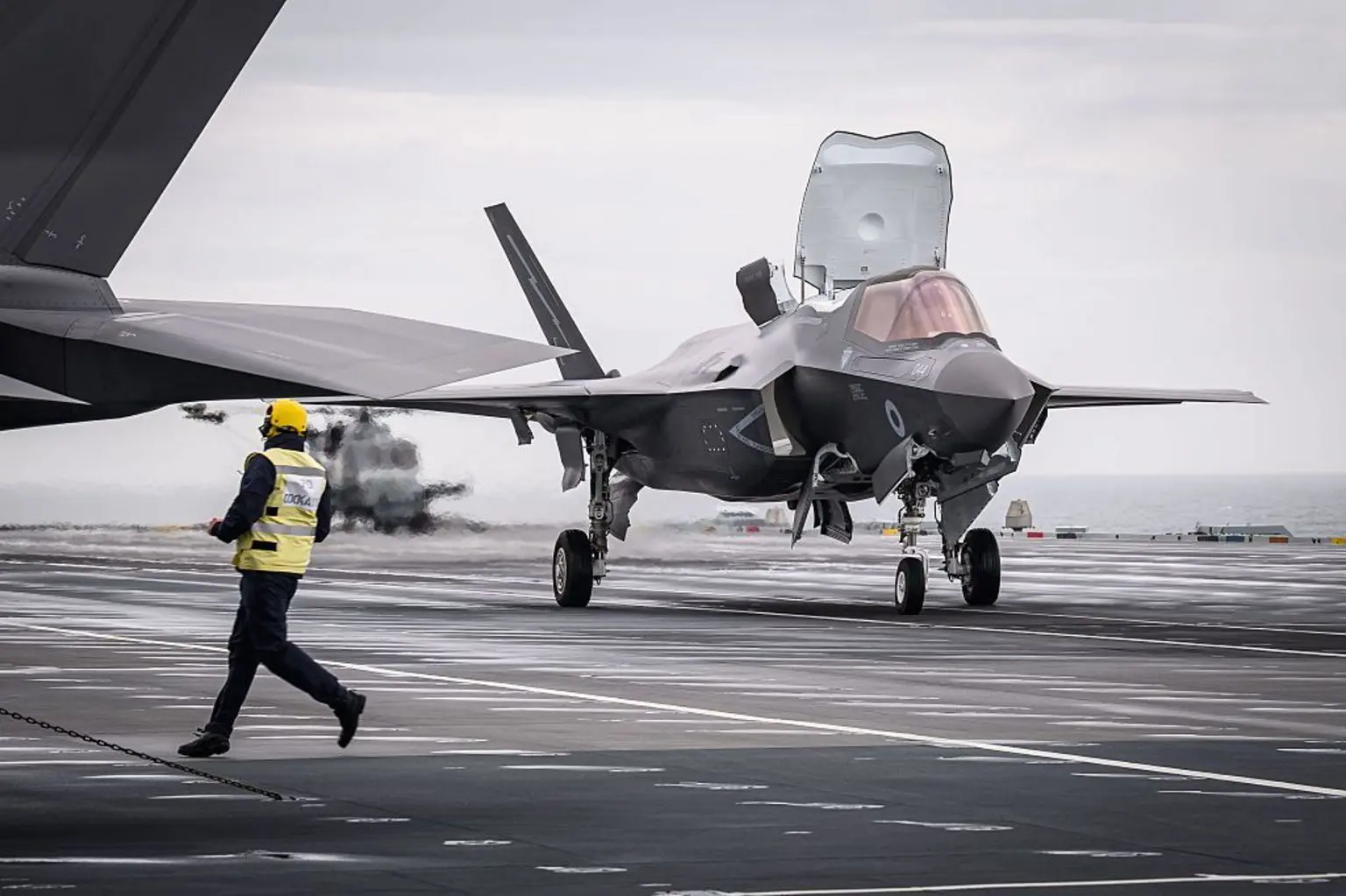 Член екіпажу пробігає повз F-35B, варіант STOVL (короткий зліт і вертикальна посадка) літака Lockheed Martin F-35, який злітає з палуби авіаносця типу