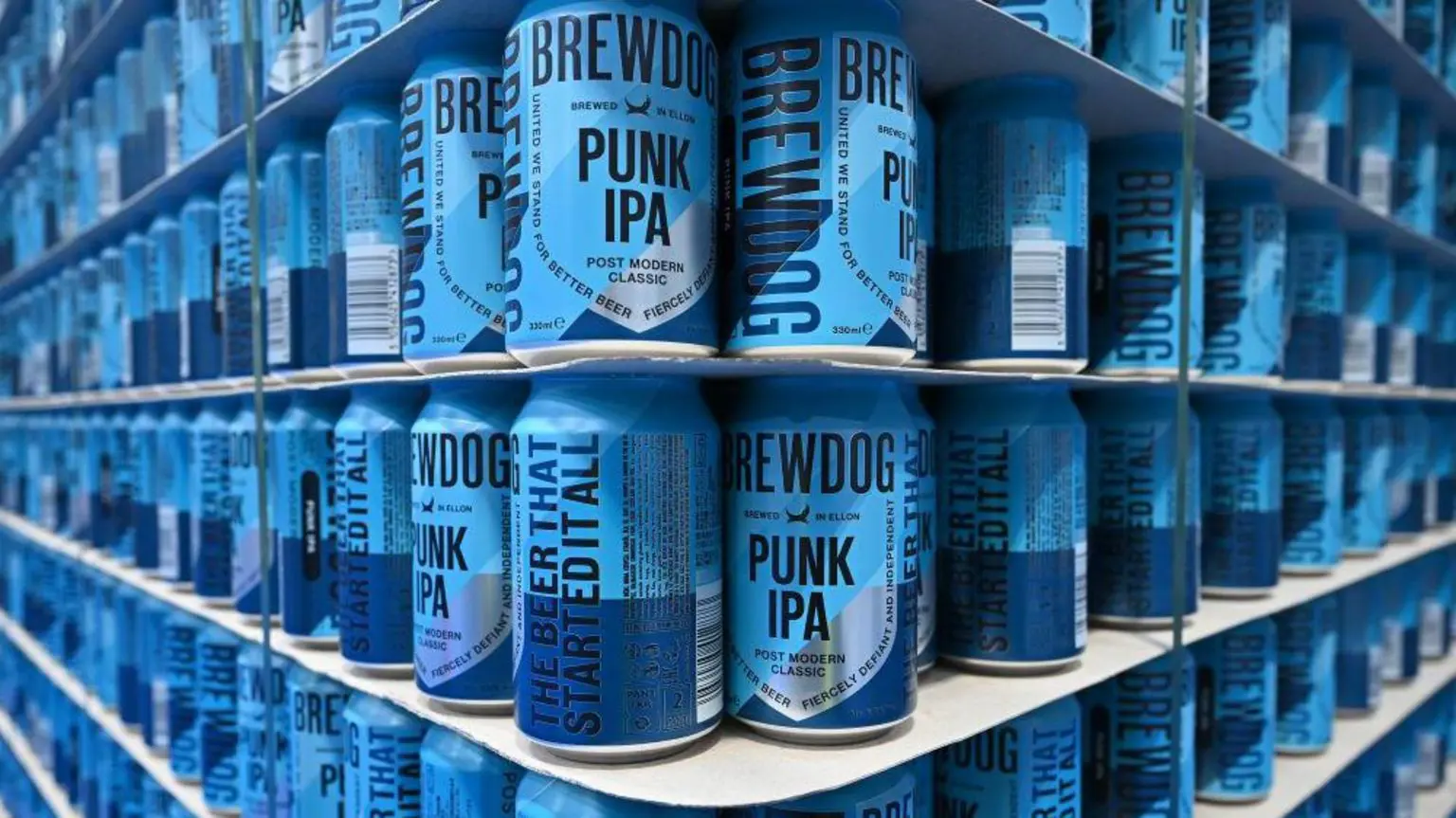 Полиці, повні банок пива Brewdog's Punk IPA. Банки двох відтінків синього.