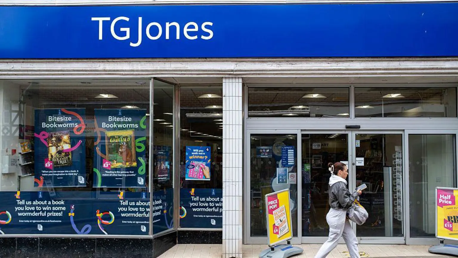 Жінка йде перед вітриною магазину TG Jones.