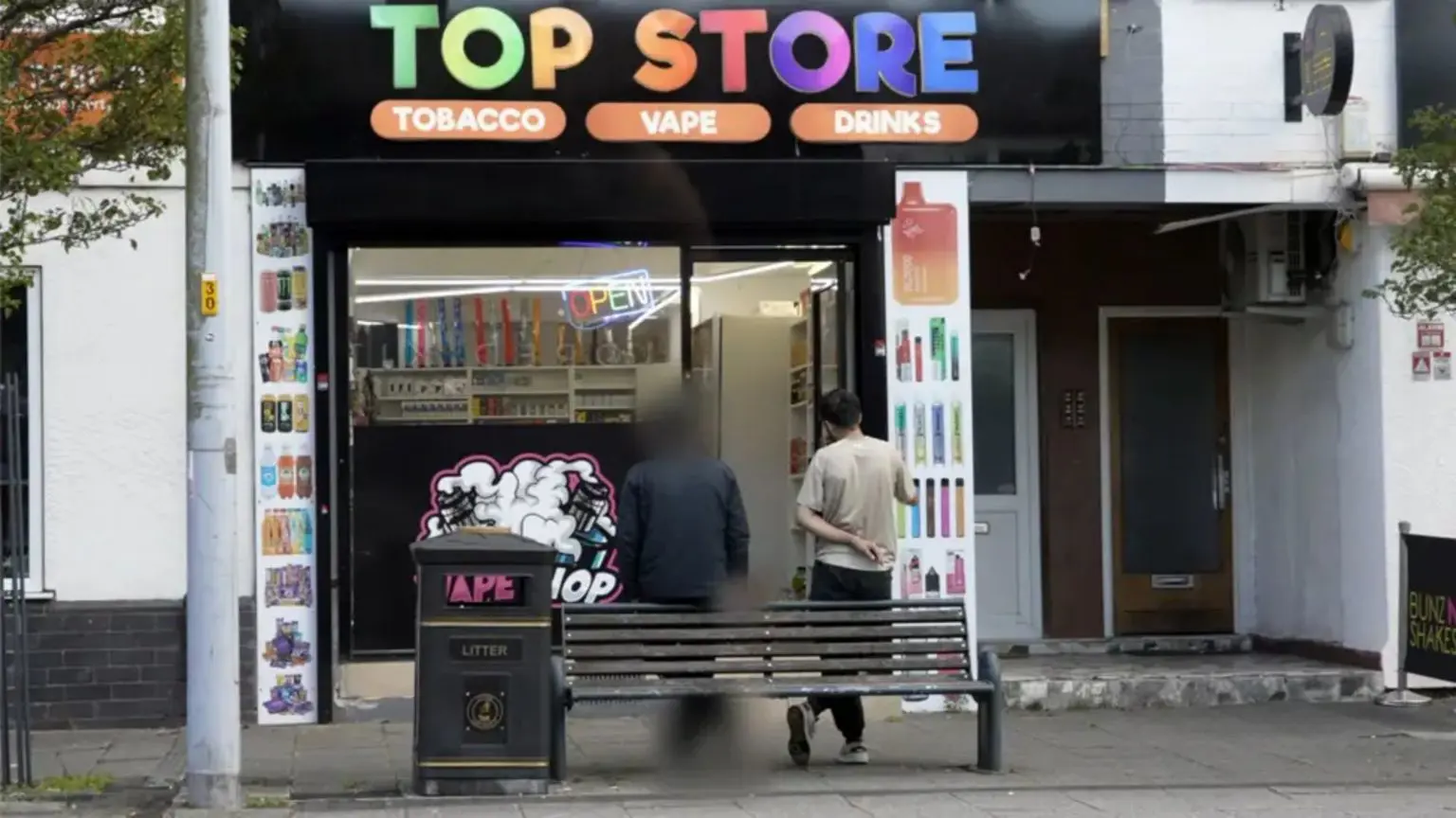 Двоє чоловіків стоять біля вейп-шопу під назвою Top Store