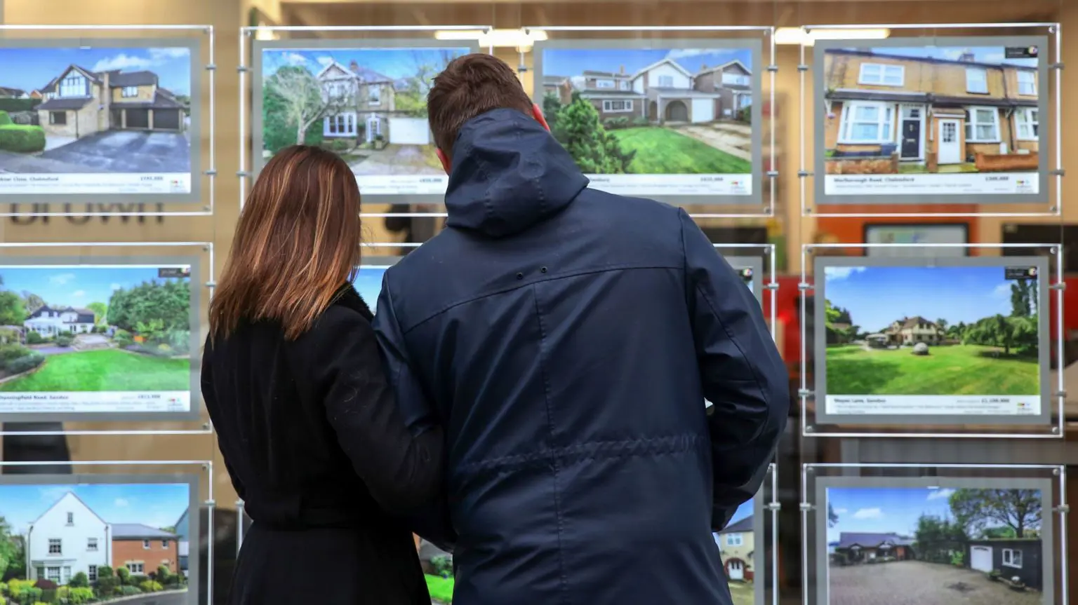 Пара розглядає будинки на продаж у вікні агента з нерухомості
